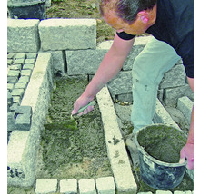 Handwerker verfugt Pflastersteine mit einer Maurerkelle