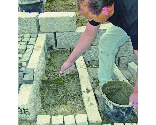 Handwerker verfugt Pflastersteine mit einer Maurerkelle