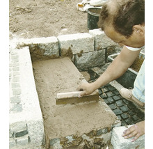 Handwerker verfugt Steine mit einem Fugenbrett im Außenbereich.
