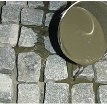 Pflastersteine werden mit Fugenmörtel gefüllt.