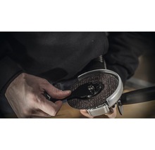 Person montiert eine Trennscheibe an einem Winkelschleifer.