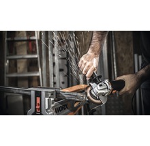 Eine Person schneidet mit einem Winkelschleifer ein Metallstück, das in einem Schraubstock fixiert ist. Es entstehen Funken.