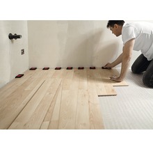 Mann verlegt Laminatboden mit Abstandshaltern an der Wand