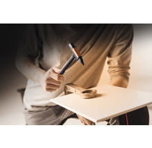 Mann benutzt Hammer und Fliesenschneider zum Bearbeiten einer Fliese