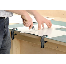 Zuschneiden einer Platte mit einem Cutter an einer Werkbank mit Schraubzwingen fixiert