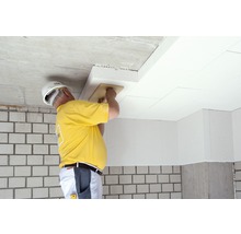 Handwerker montiert Dämmplatten an der Decke mit einem Reibebrett für Wärmedämmung.
