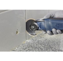 Eine oszillierende Multifunktionswerkzeug schneidet eine Fliese.