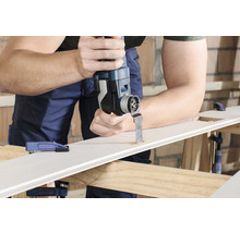 Mann schneidet mit einem Multifunktionswerkzeug ein Loch in ein Werkstück