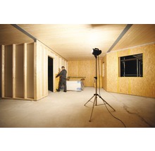 Rohbau eines Raumes mit Holzverkleidung, Beleuchtung und einem Arbeiter