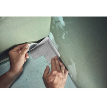 Person verlegt Dichtband in einer Ecke