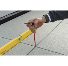 Eine Person markiert Fugen zwischen Terrassenplatten mit einem Fugenkreuz und einer Wasserwaage.