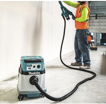Handwerker bei der Arbeit mit einem Wandspachtelschleifer und einem Makita Staubsauger zur Staubabsaugung.