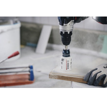 Bohrmaschine mit Lochsäge bohrt ein Loch in eine Fliese. Bosch Logo