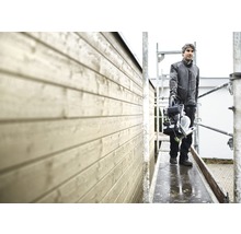 Ein Mann steht auf einem Gerüst und hält eine Kappsäge.