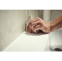 Hand glättet Silikonfuge mit Fugenglätter zwischen Waschbecken und Wandfliesen