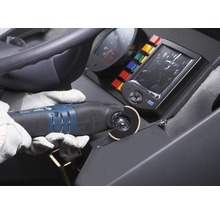 Bediener mit Schutzhandschuhen verwendet ein Multifunktionswerkzeug zum Schneiden eines Materials auf einer Baustelle