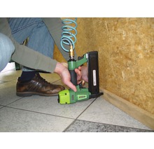 Eine Person verwendet einen Druckluftnagler für Holzarbeiten.