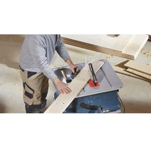 Eine Person schneidet ein Holzbrett mit einer Tischkreissäge.