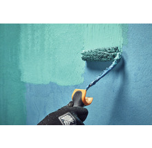 Eine Person streicht mit einer Farbrolle eine Wand.