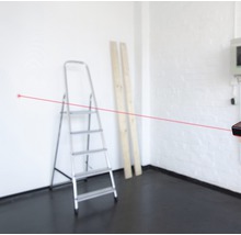 Raum mit Leiter, Holzbrettern und Laser-Entfernungsmesser mit rotem Laserstrahl