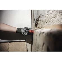 Eine Person verwendet ein Laser-Nivelliergerät an einer Wand, um ein Projekt auszurichten.