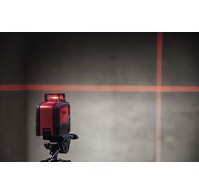 Kreuzlinienlaser auf Stativ mit Laserlinien an der Wand