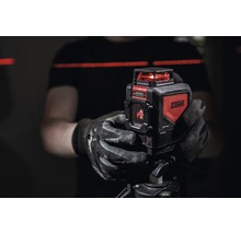 Person hält einen JC Schwarz Kreuzlinienlaser auf einem Stativ