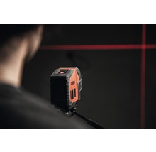 Kreuzlinienlaser projiziert rote Laserlinien an eine Wand.