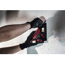 Eine Person befestigt einen Kreuzlinienlaser an einer Wand.