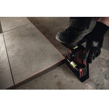 Person verlegt Fliesen mit einem Linienlaser zur Ausrichtung.