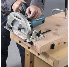 Eine Person schneidet mit einer Handkreissäge ein Holzbrett auf einer Werkbank.