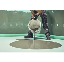 Handwerker gießt Ausgleichsmasse auf einen Untergrund