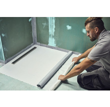 Mann verlegt Abdichtungsbahn im Badezimmer