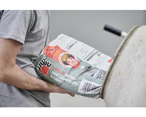 Person trägt Sack mit Fertigbeton für Garten- und Landschaftsbau