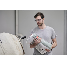 Mann schüttet Estrichmörtel in einen Betonmischer.