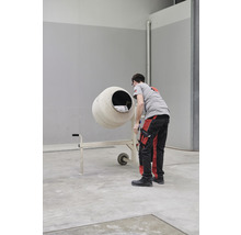 Ein Mann steht neben einem Betonmischer in einem Lagerraum.