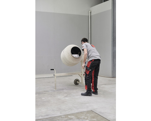 Ein Mann steht neben einem Betonmischer in einem Lagerraum.