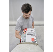 Mann schüttet Garten- und Landschaftsbaubeton in einen Betonmischer.