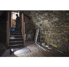 Kellerraum mit Steintreppe, Arbeitsleuchte, Werkzeugkoffer und Handwerker