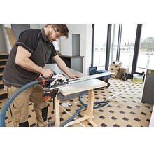 Handwerker sägt mit einer Handkreissäge ein Werkstück auf einer Werkbank. Ein Absaugschlauch ist an der Säge befestigt.