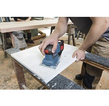 Eine Person schleift mit einem Elektroschleifer ein Werkstück.