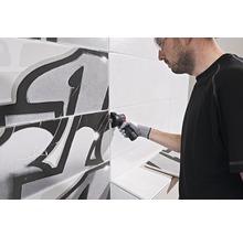 Handwerker bearbeitet Fliesen mit einem Winkelschleifer in einem Badezimmer.