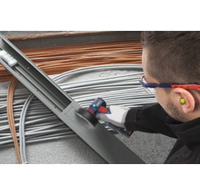 Elektriker bearbeitet Kabelkanal mit einem Multifunktionswerkzeug vor Kabeln