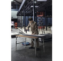 Ein Mann bohrt mit einer Bohrmaschine ein Werkstück auf einem Klapptisch.