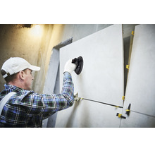 Fliesenleger mit Saugnapfwerkzeug verlegt Fliesen an einer Wand