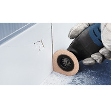 Eine Person verwendet ein Multifunktionswerkzeug zum Entfernen von beschädigten Fliesenfugen.