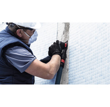 Handwerker mit persönlicher Schutzausrüstung bei der Fliesenfugenbearbeitung