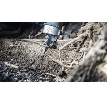 Eine Säbelsäge schneidet eine Wurzel im Erdreich.