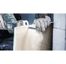 Eine Person schneidet eine Gipskartonplatte mit einer Säge.