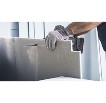 Eine Person schneidet mit einer Stichsäge eine Gipskartonplatte.